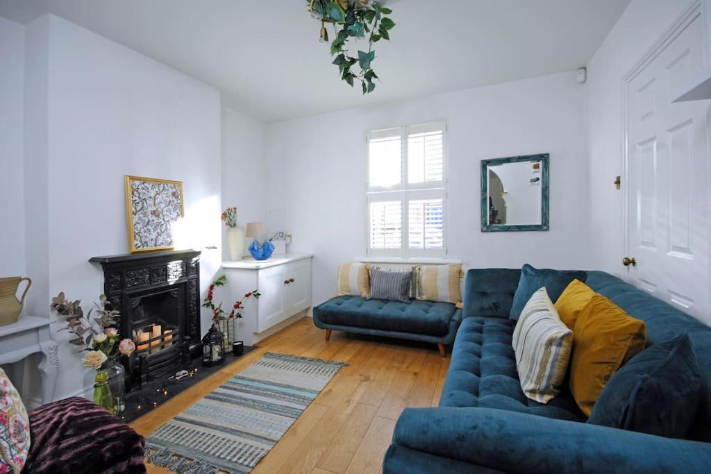 a living room with a blue couch and a fireplace at Ivy Cottage in Henley on Thames