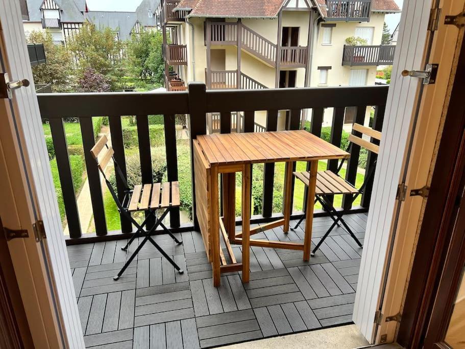 d'une table en bois et de deux chaises sur un balcon. dans l'établissement Le Balbec - Appartement Cosy, à Cabourg