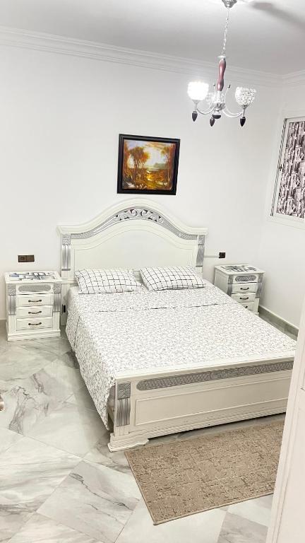 Tetouan Relax Apartement في تطوان: غرفة نوم بيضاء بسرير وليلتين