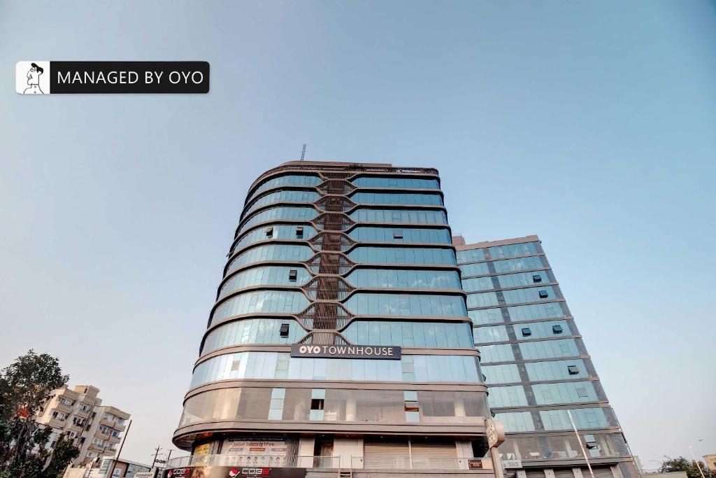 a tall glass building with a sign on it at Townhouse Akota Mujmahuda Road - Managed by Company in Vadodara