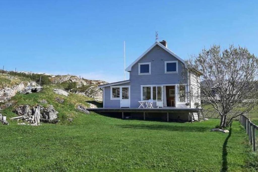 una casa azul en una colina con un patio de césped en Idyllic and peaceful Family Home, en Tromsø