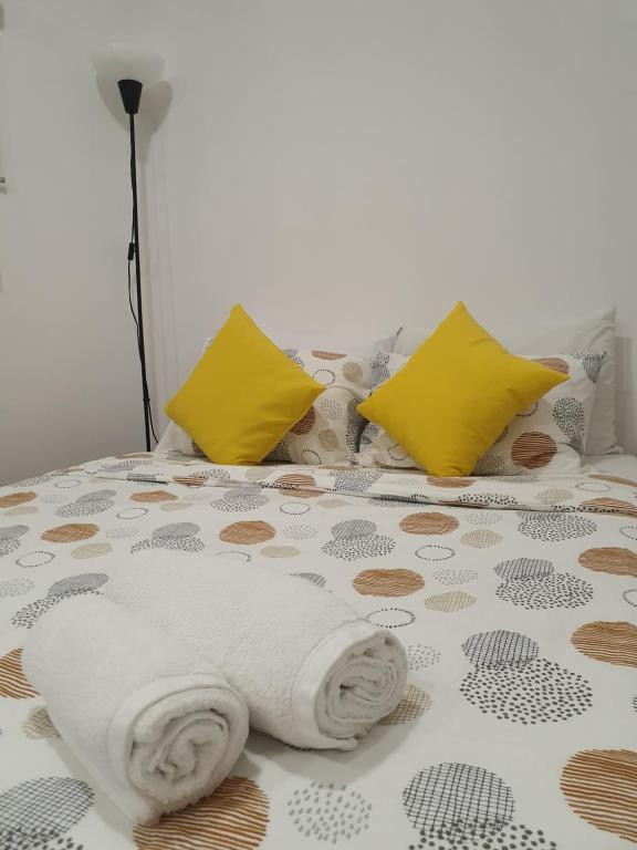 ein Bett mit gelben Kissen und einer weißen Decke in der Unterkunft Zabava Sacavém in Sacavém