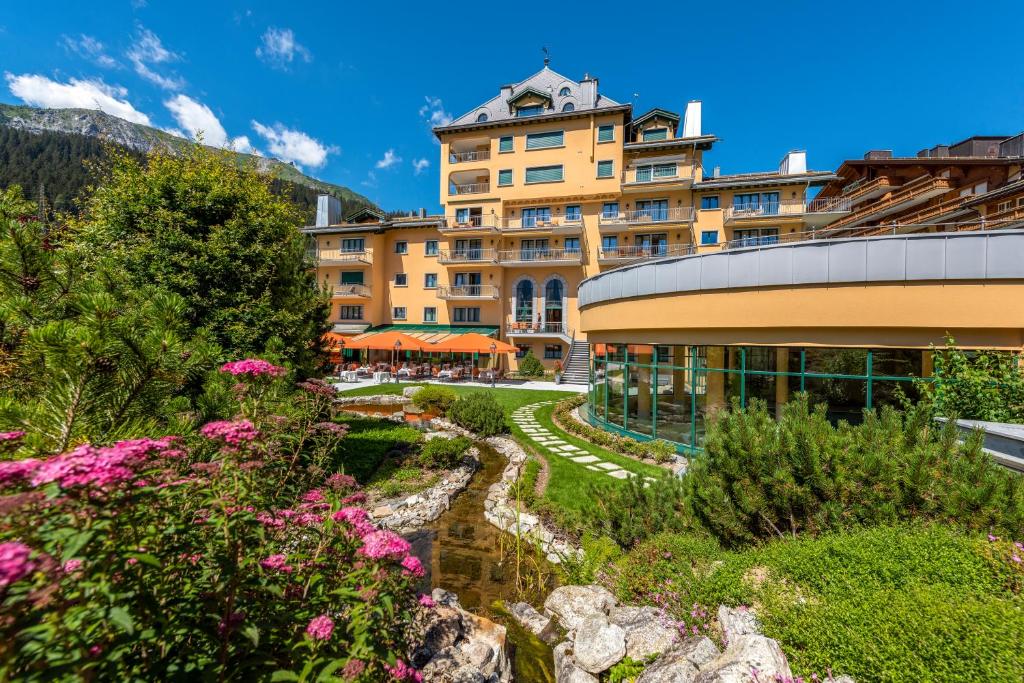 um hotel com um jardim em frente a um edifício em Hotel Vereina em Klosters