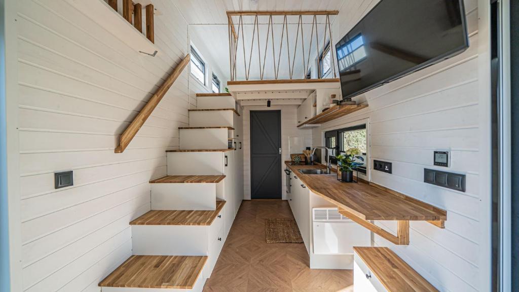 a tiny house with stairs and a tv on the wall at Tinyhaus Marie von Tinyhaus Steinhude in Steinhude