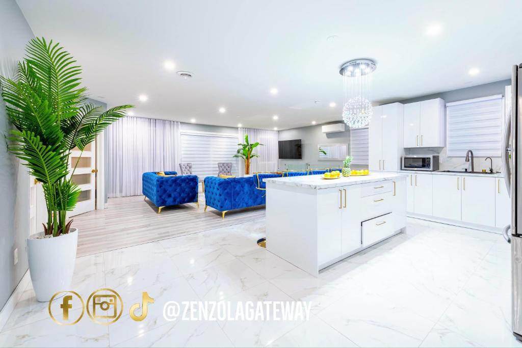cocina y sala de estar con armarios blancos y sillas azules en Zenzola's gateway Near Downtown, en Longueuil