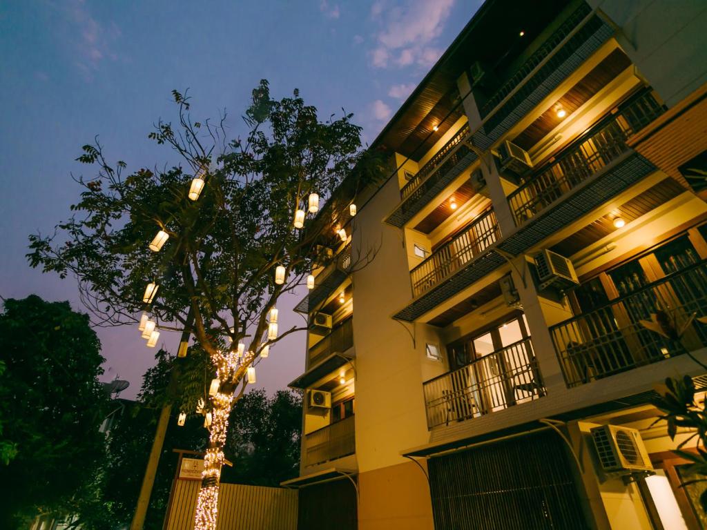 a tree in front of a building with lights on it at Rendezvous Classic House in Chiang Mai