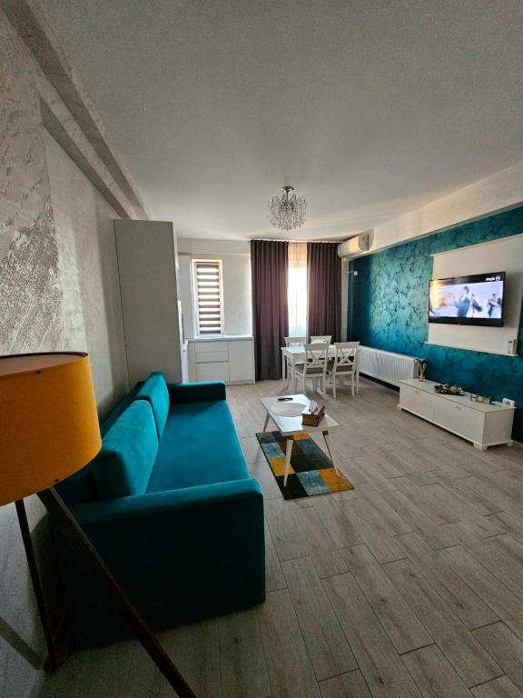 een woonkamer met een blauwe bank en een tv bij Sunrise Residence in Mamaia Nord – Năvodari