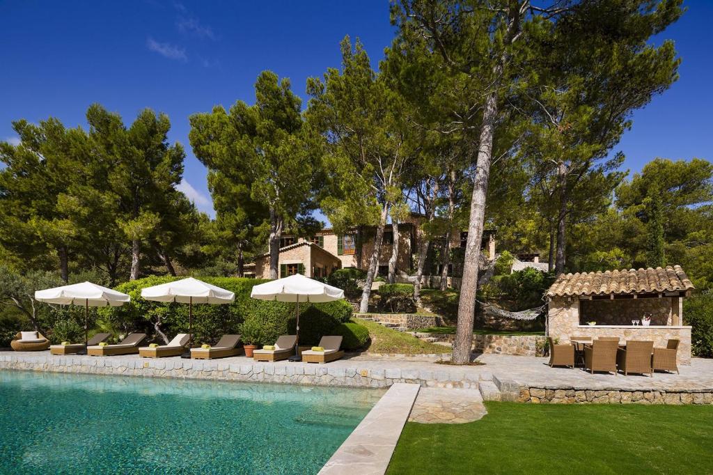 una piscina con tumbonas y sombrillas en Astounding Mallorca Villa La Mejor Vista 5 Bedrooms All Inclusive & Private Heated Pool Banyalbufar, en Banyalbufar