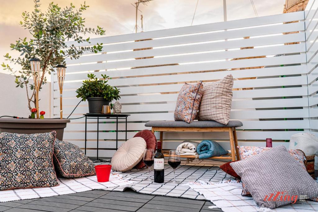 a patio with pillows and a bench and a wall at A modern Maltese townhouse in Siggiewi in Siġġiewi