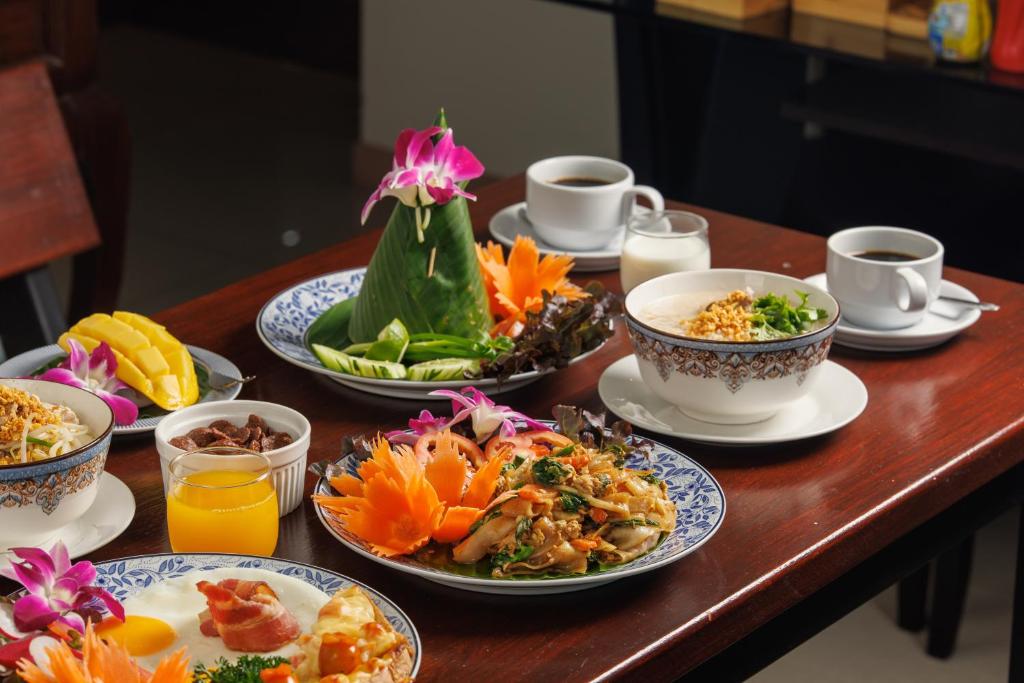 a table with plates of food and cups of orange juice at Rendezvous Classic House in Chiang Mai