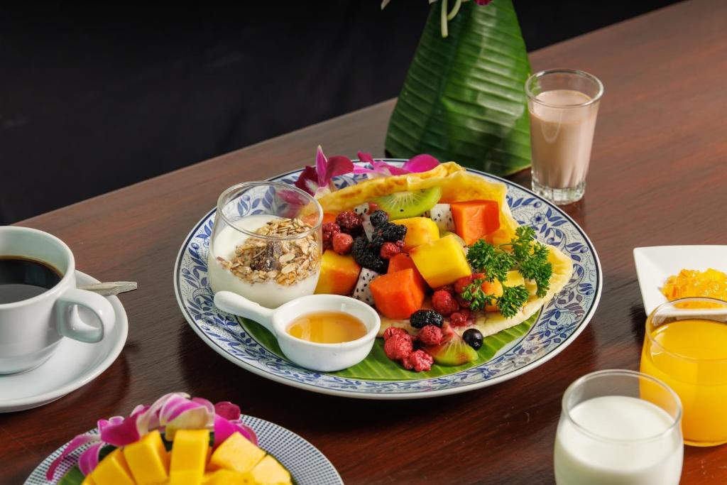 a table with a plate of fruit salad and a cup of coffee at Rendezvous Classic House in Chiang Mai