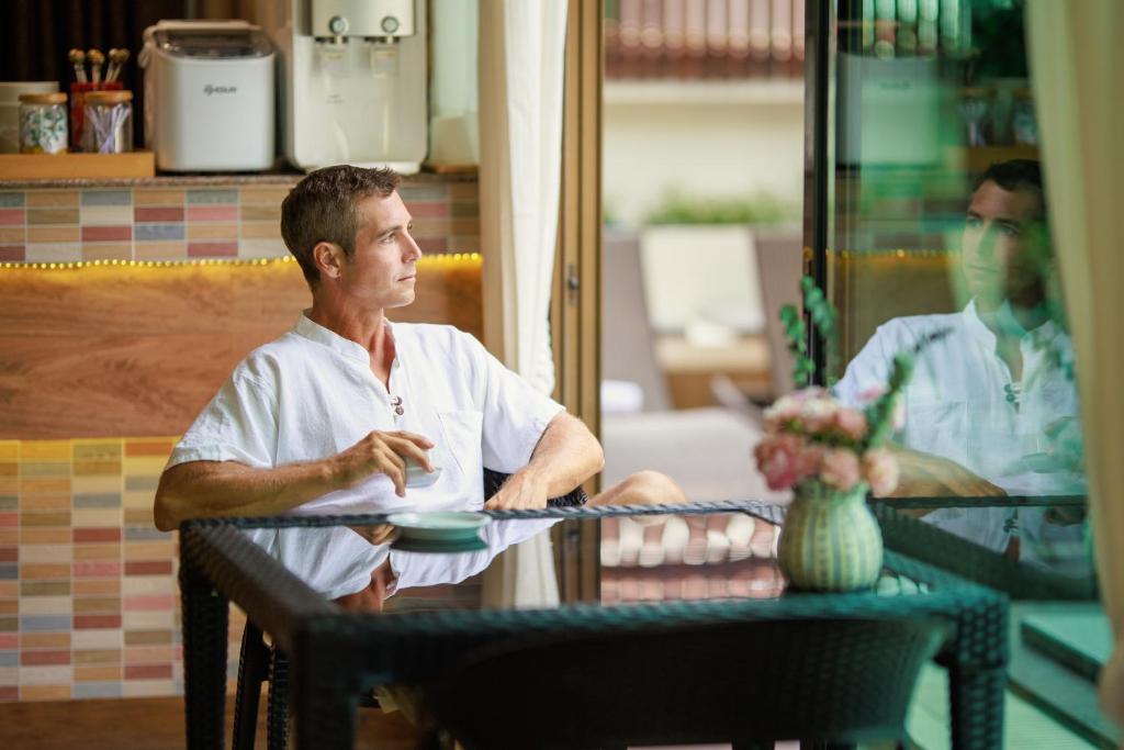 a man sitting at a table with a plate at Rendezvous Classic House in Chiang Mai