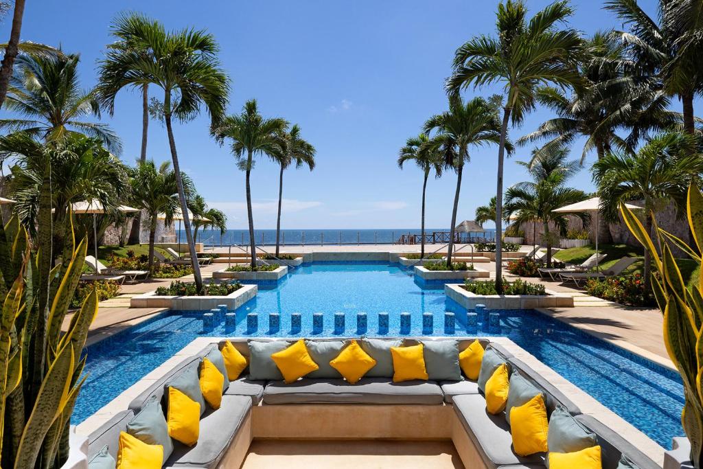a pool at the resort with yellow pillows and palm trees at Azul Villa Casa del Mar - Gourmet All Inclusive by Karisma in Puerto Morelos