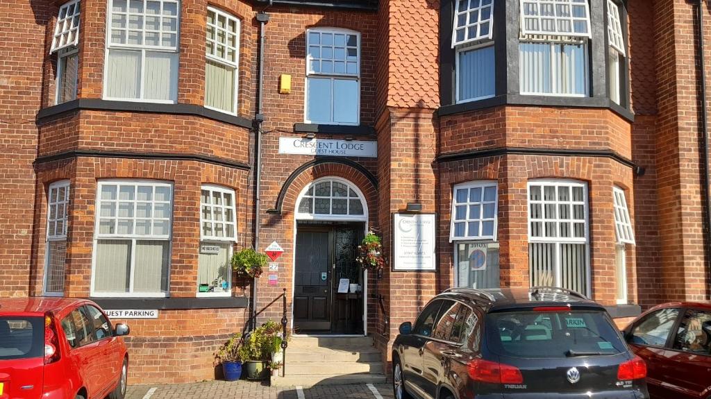 a brick building with cars parked in front of it at Crescent Lodge Guest House in Whitby