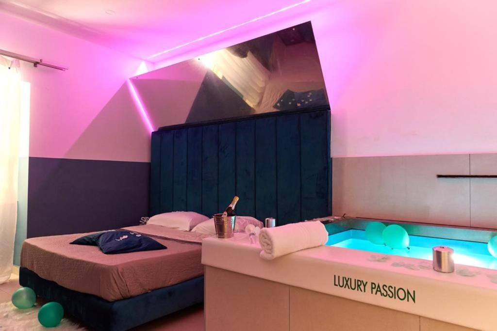 een kamer met een bed en een bad met roze verlichting bij Hotel Melydà in Pozzuoli