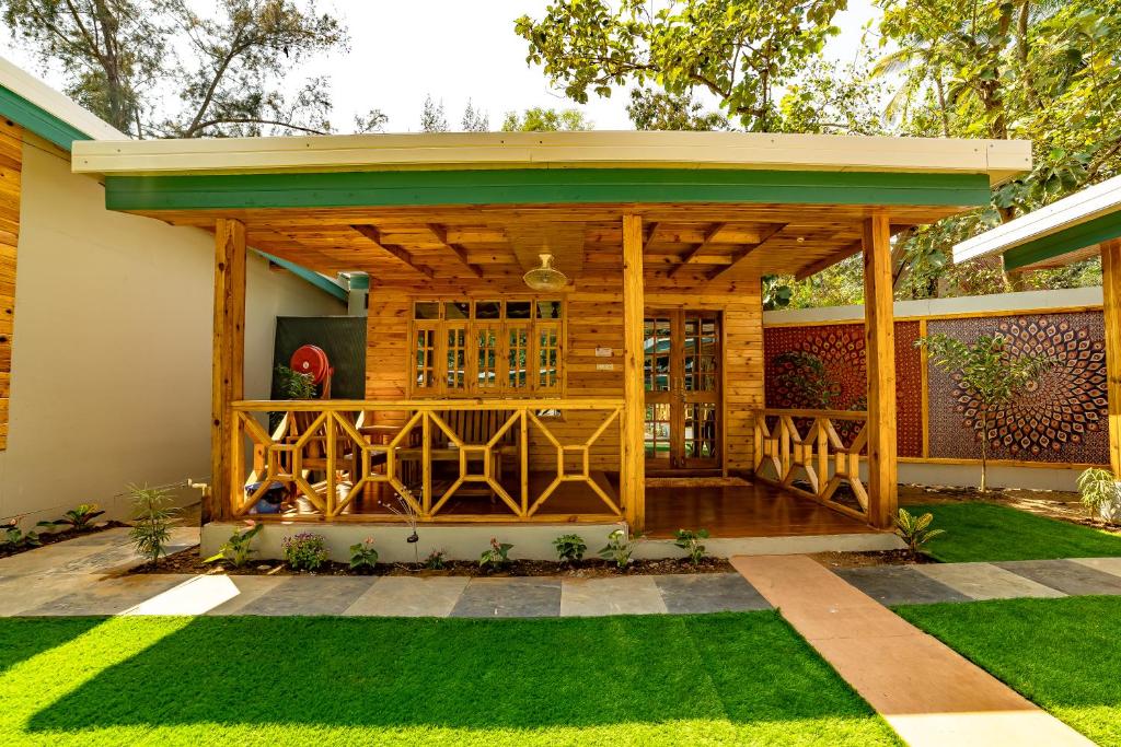 a wooden pergola on a house with grass at Oxygen Palolem in Palolem