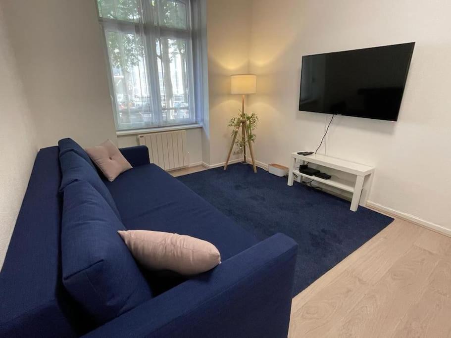 un salon avec un canapé bleu et une télévision à écran plat dans l'établissement Strasbourg Contades Clemenceau : ), à Strasbourg