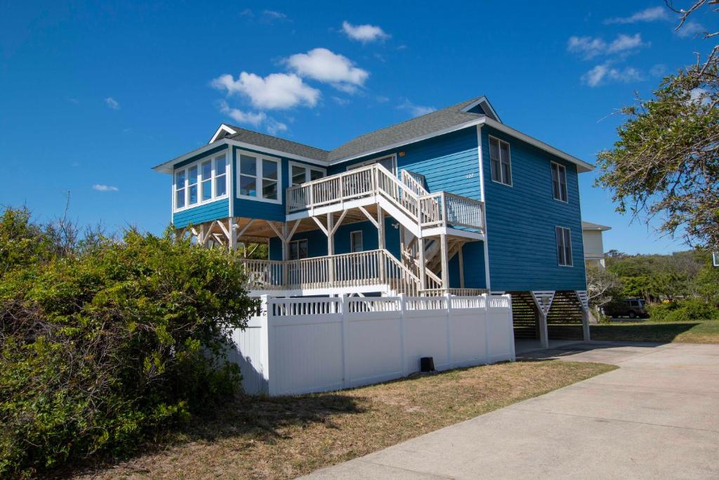 una casa blu con una recinzione bianca davanti di Semi-Oceanfront, Private Pool, Poolside Bar, Hot Tub, Ocean Views! T1, Sailaway a Duck