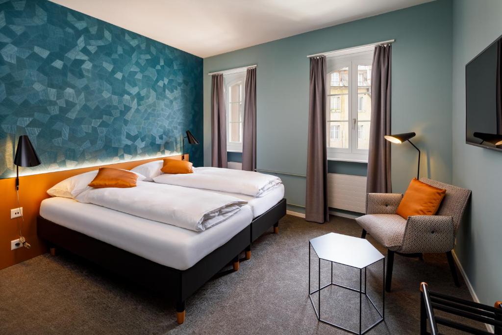 a hotel room with two beds and a chair at Hotel Münzgasse - Self Check-in in Luzern