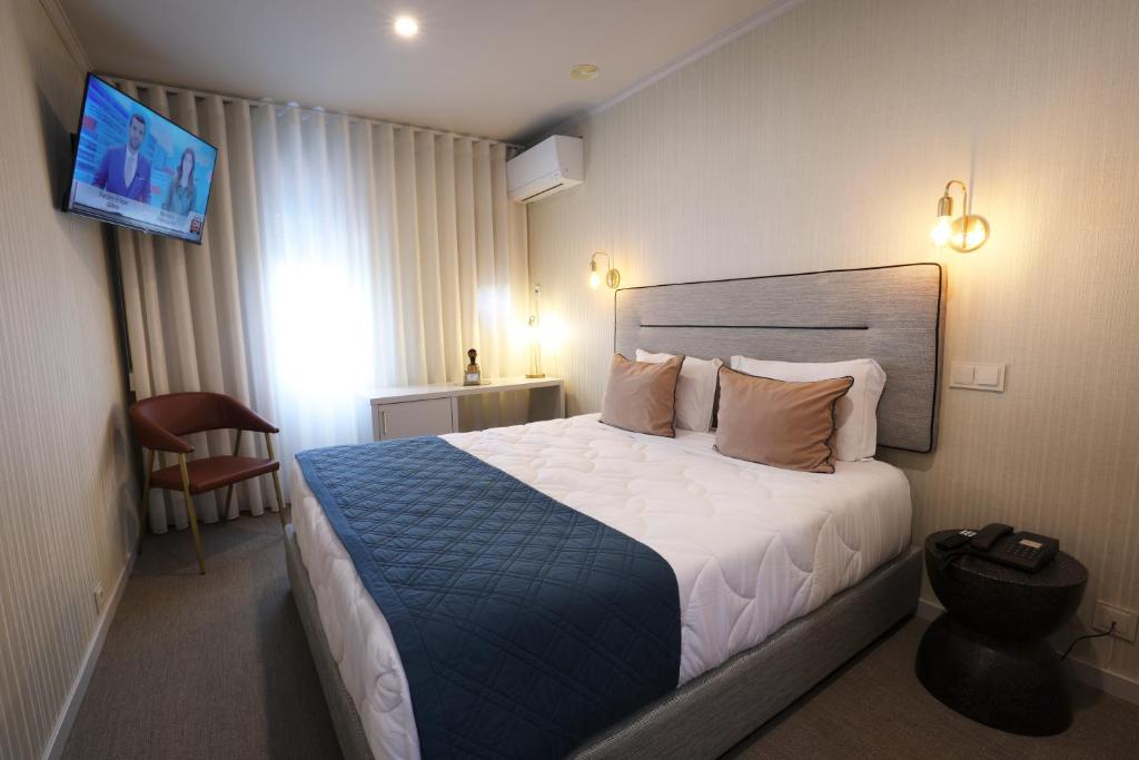 Una habitación de hotel con una cama y un televisor. en Hotel America, en Oporto