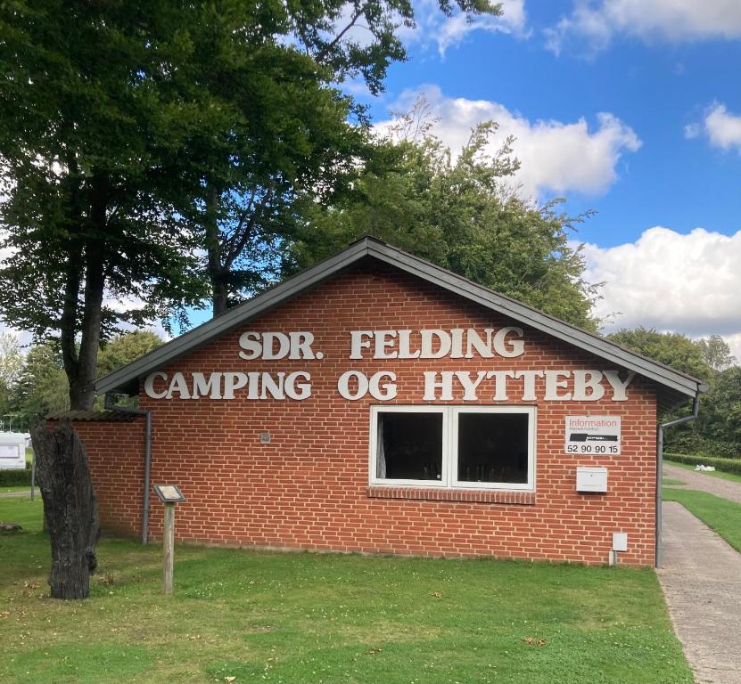 Sønder Felding的住宿－Sdr. Felding camping & hytteby，砖楼边的标志