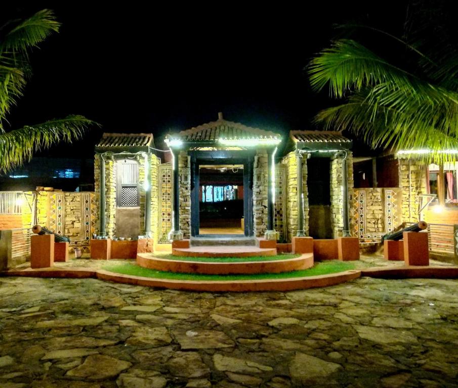 a building at night with palm trees and lights at Shilpgram in Bhuj