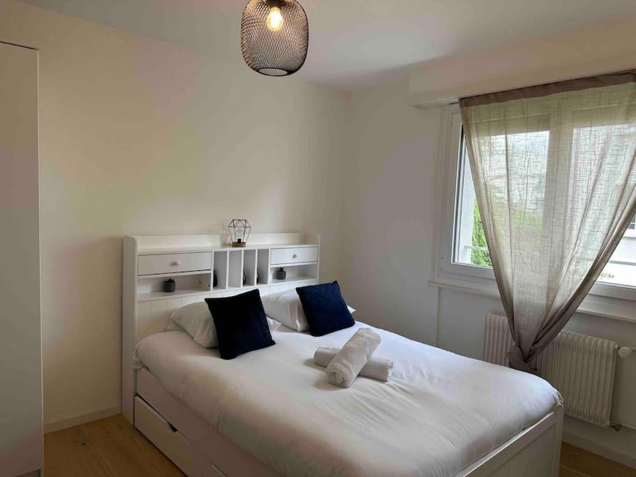 1 dormitorio con 1 cama blanca grande con almohadas azules en Studio proche de la gare !, en Lausana