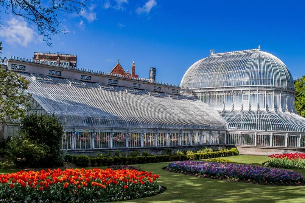 a large glass greenhouse with flowers in a garden at Beautiful Apartment in the city center in Belfast