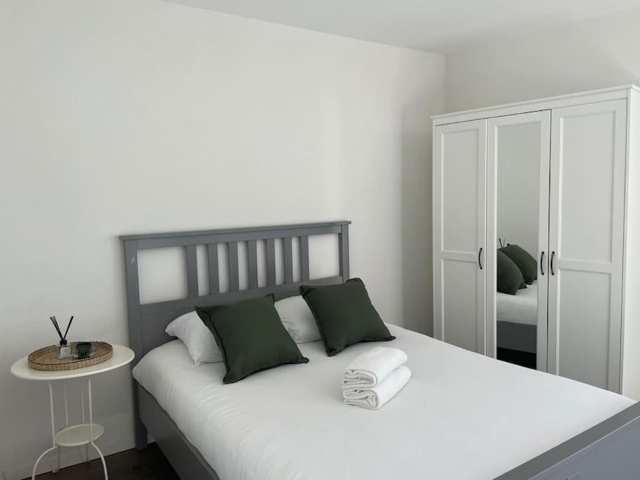 1 dormitorio con cama blanca y almohadas verdes en Proche Lausanne: Studio bien équipé, en Prilly