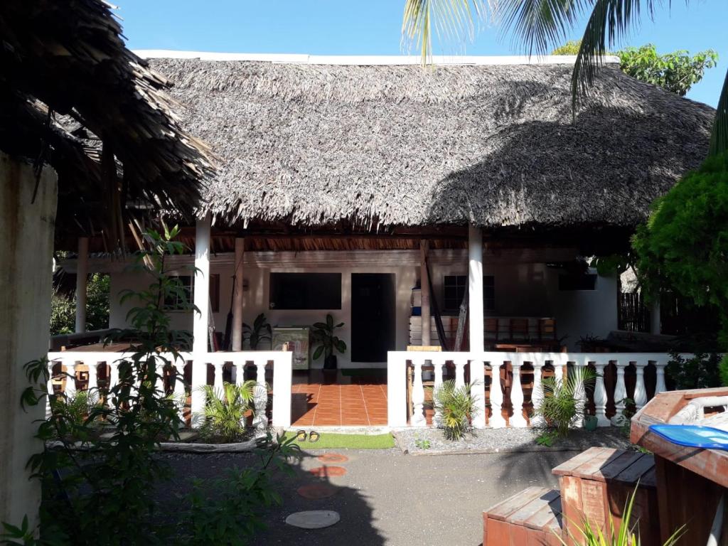 a house with a thatched roof and a fence at Backpackers Hostel in Sipacate