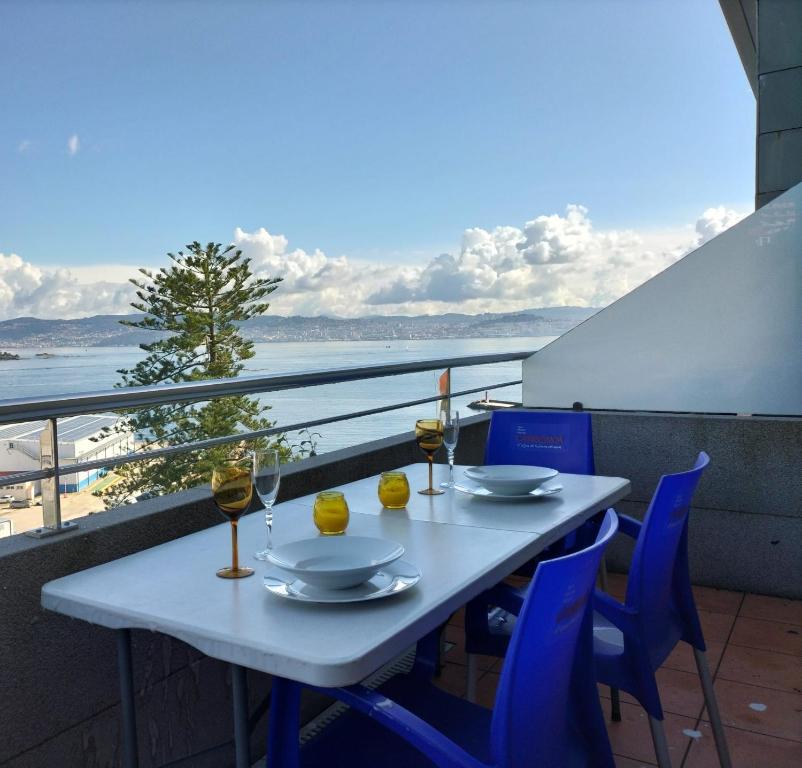 a table with two glasses of wine on a balcony at Apartamento Punta Balea in Cangas de Morrazo