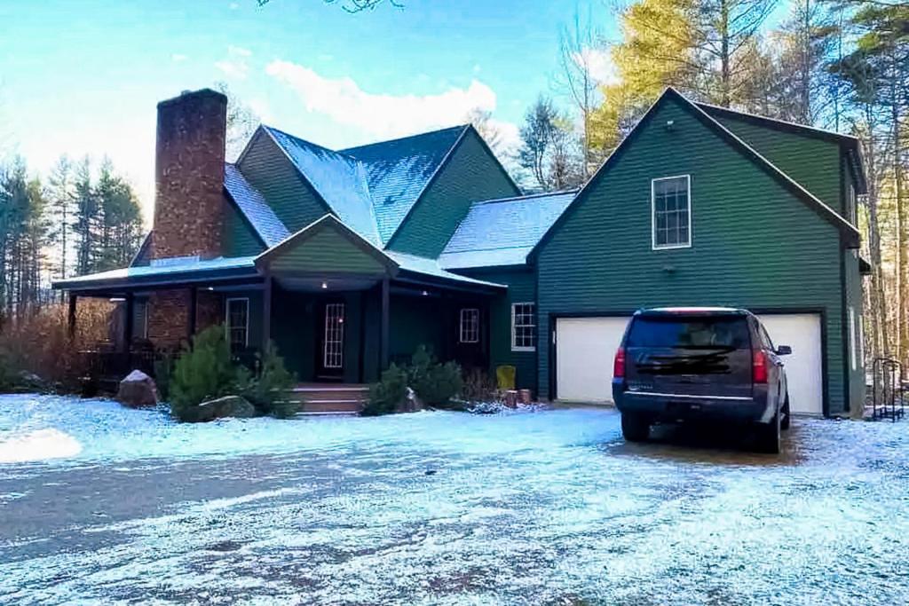 a green house with a car parked in the driveway at Ski You Later in Strattonwald