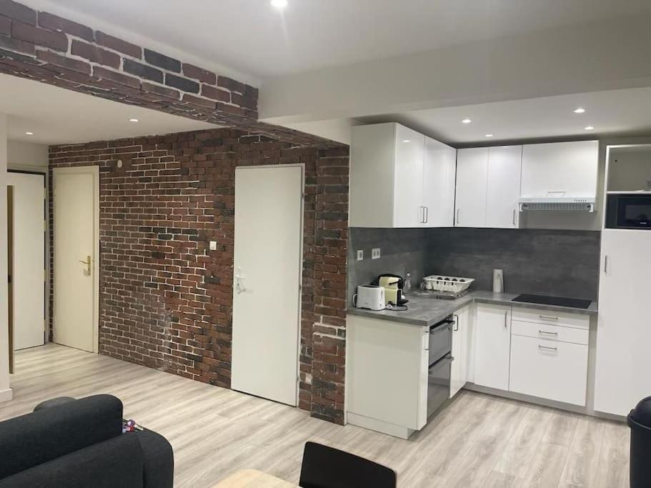 une cuisine avec des placards blancs et un mur en briques dans l'établissement Super Appart Strasbourg 6 pers centre-ville idéal, à Strasbourg
