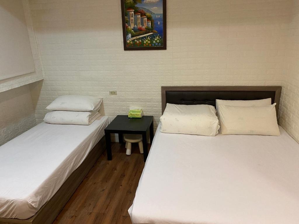 two beds in a room with a table between them at EZ Stay Hotel in Taipei