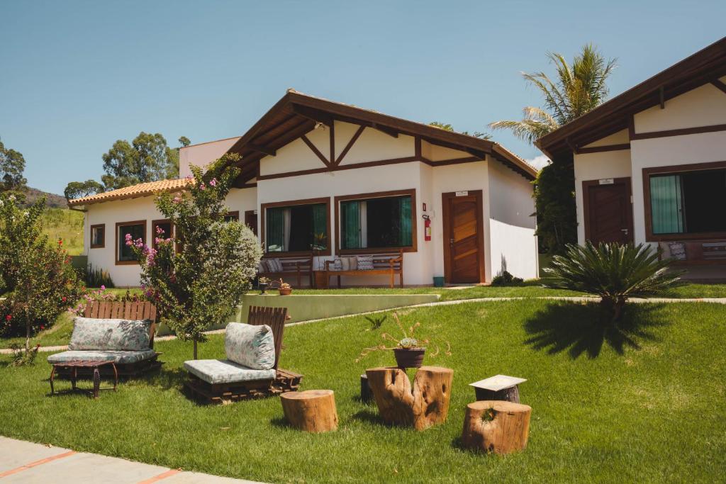 ein Haus mit einem Hof mit zwei Stühlen und Holzscheiten in der Unterkunft Pousada Vale do Chapéu in Capitólio