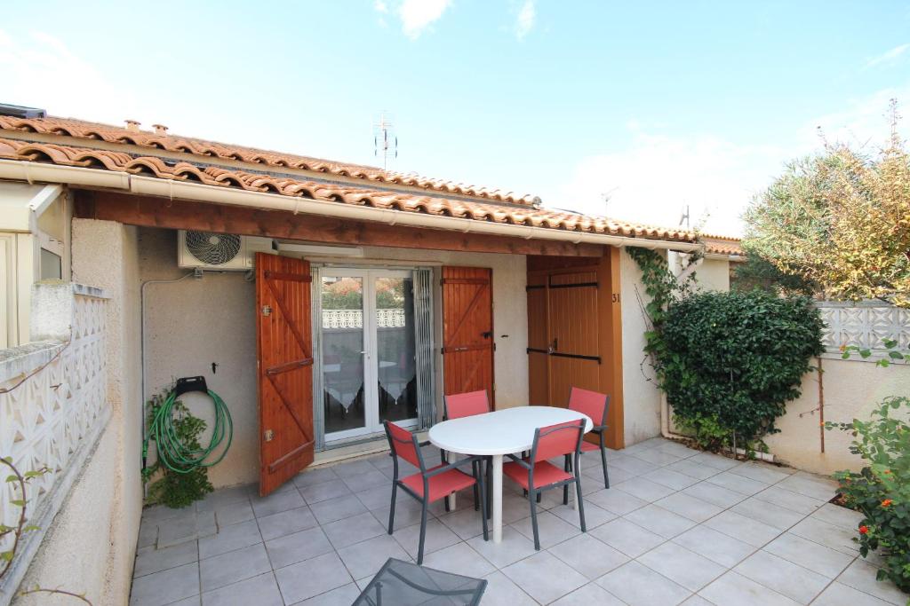 un patio avec une table et des chaises sur un balcon dans l'établissement Maison de vacances, 4 à 5 couchages, cuisine séjour climatisé dans résidence avec piscine, les Jardins de Portiragnes, 500m de la mer, LRJP31, à Portiragnes