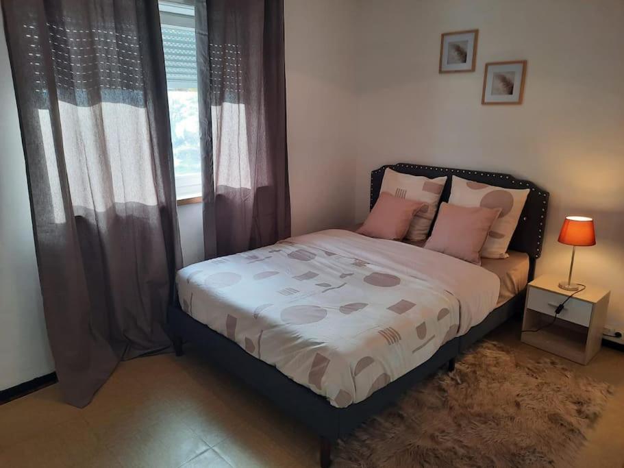Un dormitorio con una cama con almohadas rosas y una ventana en Chambre meublée, en Poissy