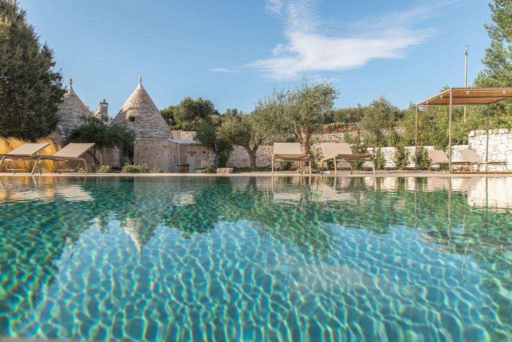 a swimming pool with blue water in front of a house at Trulli Mest'Andrea alle lame in Noci