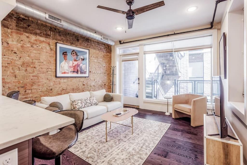 a living room with a white couch and a brick wall at Artist Gallery Downtown 2Bed 2Bath Condo in Cincinnati