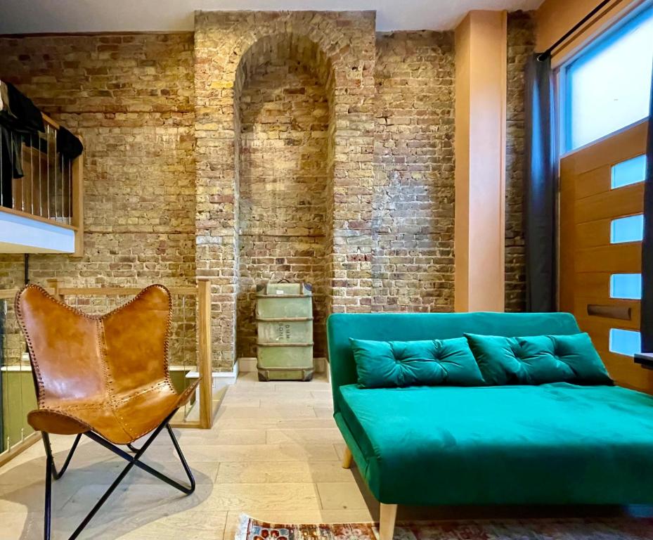 a living room with a green couch and a brick wall at Exposed Brick Flat Finsbury Park in London