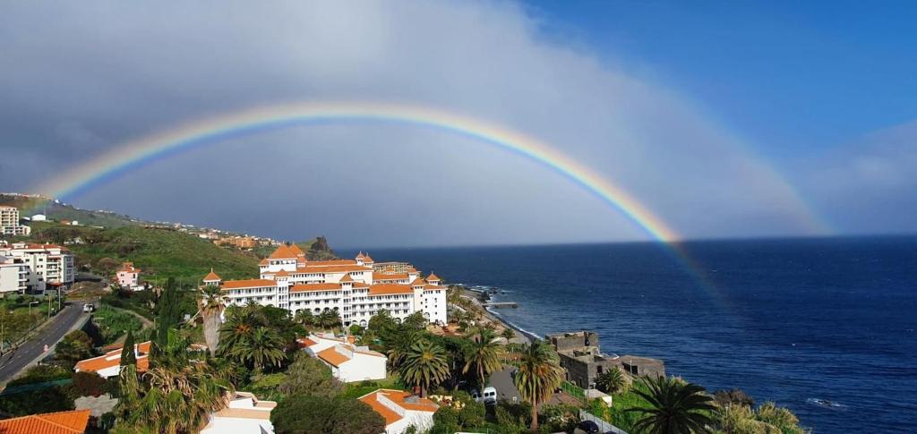un arco iris sobre una ciudad y el océano con edificios en Lua do Mar, en Caniço