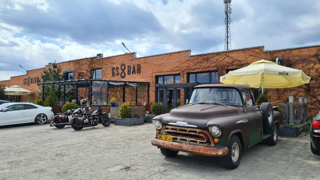 an old truck parked in front of a building with an umbrella at Es8bar in Łozina