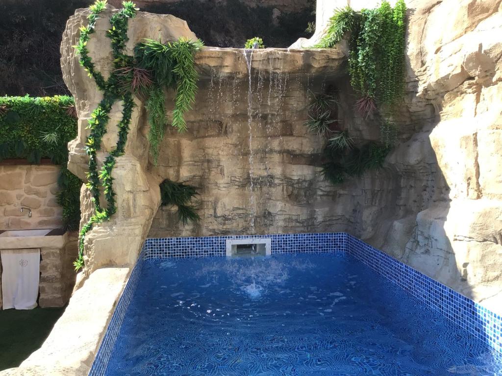 - une piscine dans un mur en pierre avec une chute d'eau dans l'établissement MEQUEDO VILLACOSTOSA, à Alcañiz