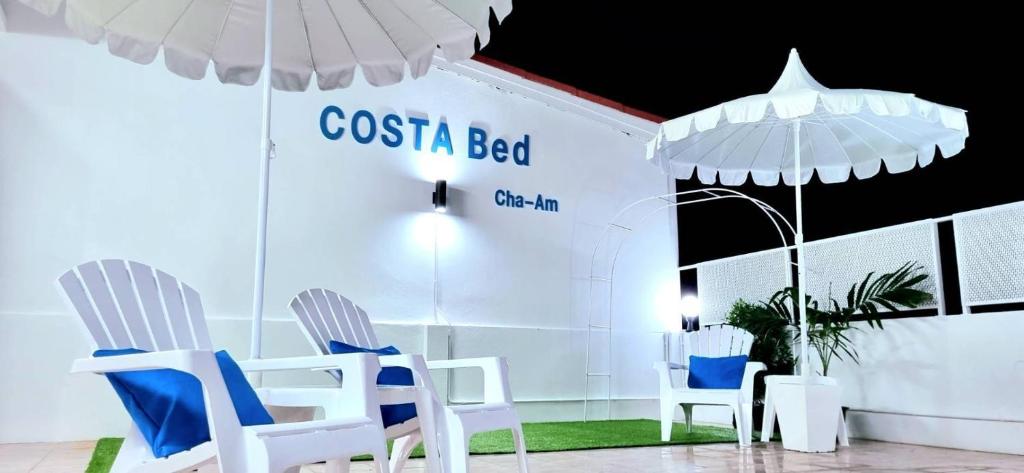 eine Gruppe von Stühlen und Sonnenschirmen in einem Zimmer in der Unterkunft Costa Bed Cha Am in Cha-am