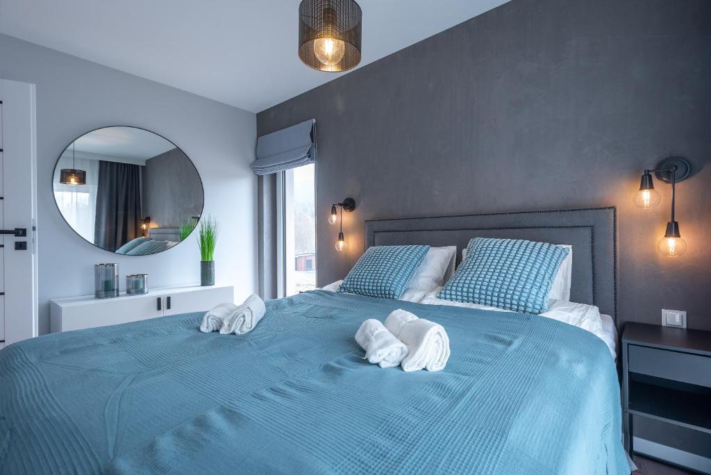 ein Schlafzimmer mit einem blauen Bett und Handtüchern darauf in der Unterkunft Apartament 5 StolarSki - 5D Apartments in Szklarska Poręba