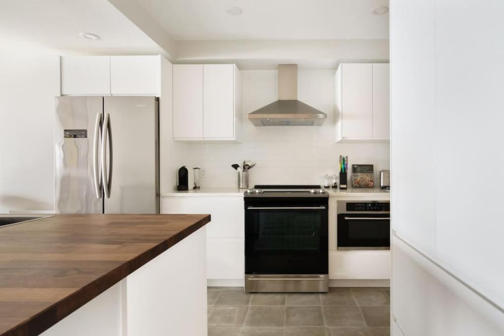 een keuken met witte kasten en een zwarte koelkast bij Luxury Condominium with Rustic Minimalist Style in Mont-Tremblant