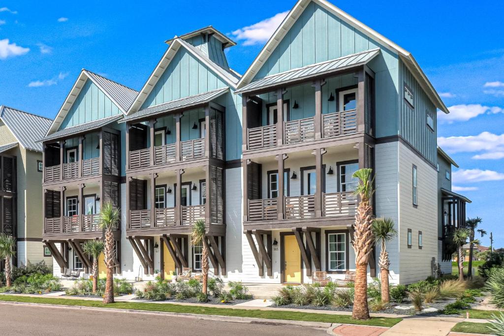 an apartment building with wooden balconies and palm trees at Palmilla Beach Resort: Luxury Gulf Getaway in Port Aransas