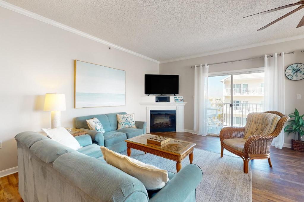 a living room with a blue couch and a fireplace at Whispering Sands 301 in Ocean City