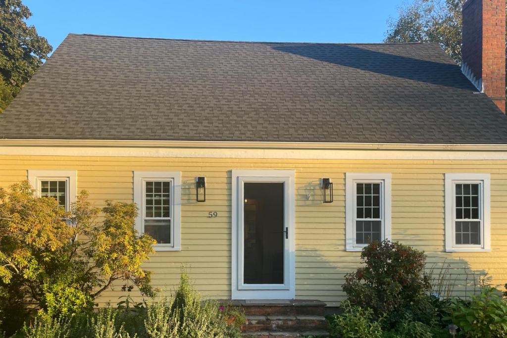 uma casa amarela com uma porta preta em Goldfinch Cottage em Newburyport