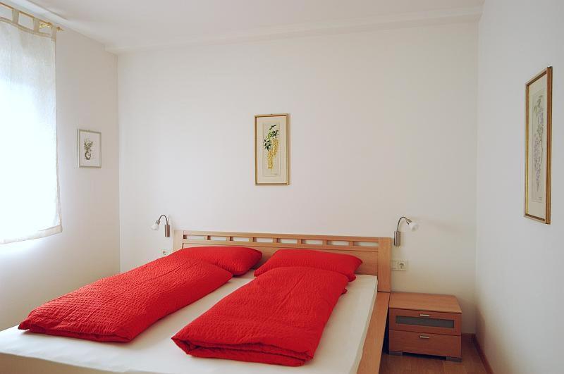 1 cama con almohadas rojas en el dormitorio en Georgshof, en Appiano sulla Strada del Vino